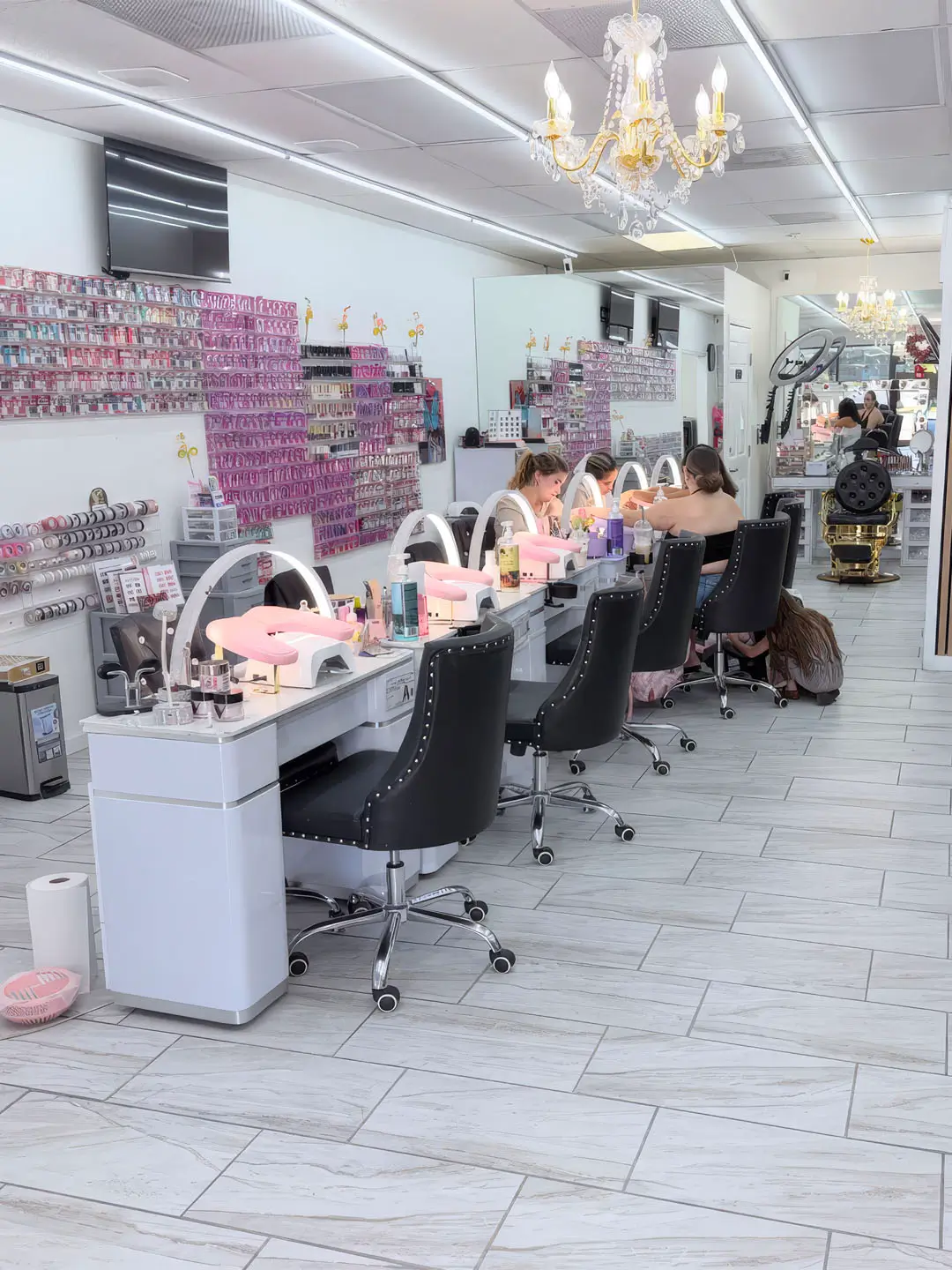 A spacious salon featuring multiple chairs and tables arranged for client services and nail styling.